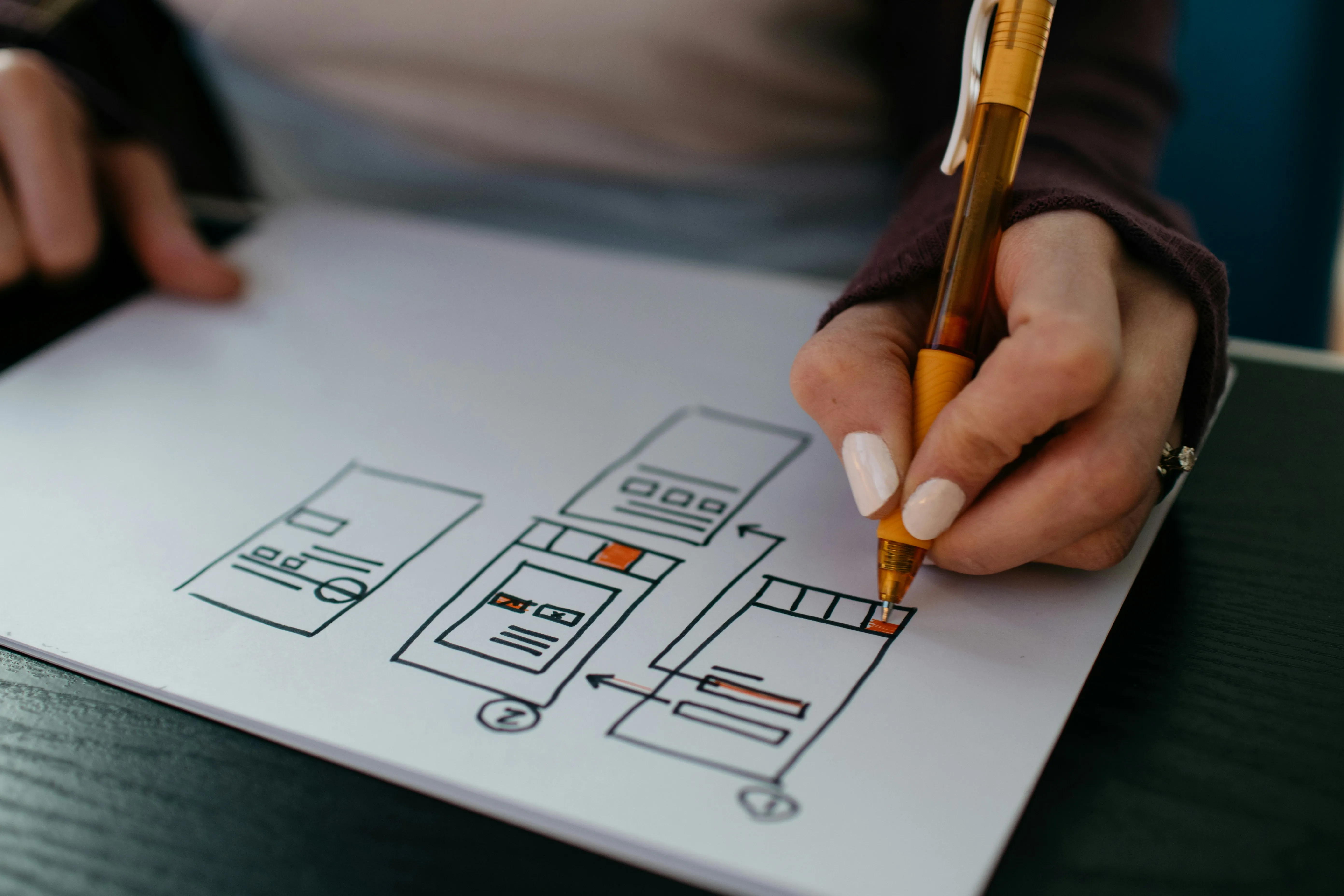 Hand drawing a mobile app interface with a pencil